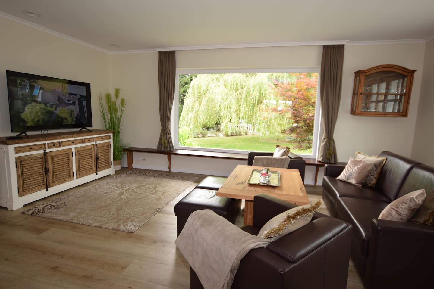 Wohnzimmer mit großem Fernseher und Blick ins Grüne